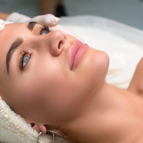 Young woman in a beauty salon. The beautician makes a facial cleansing procedure